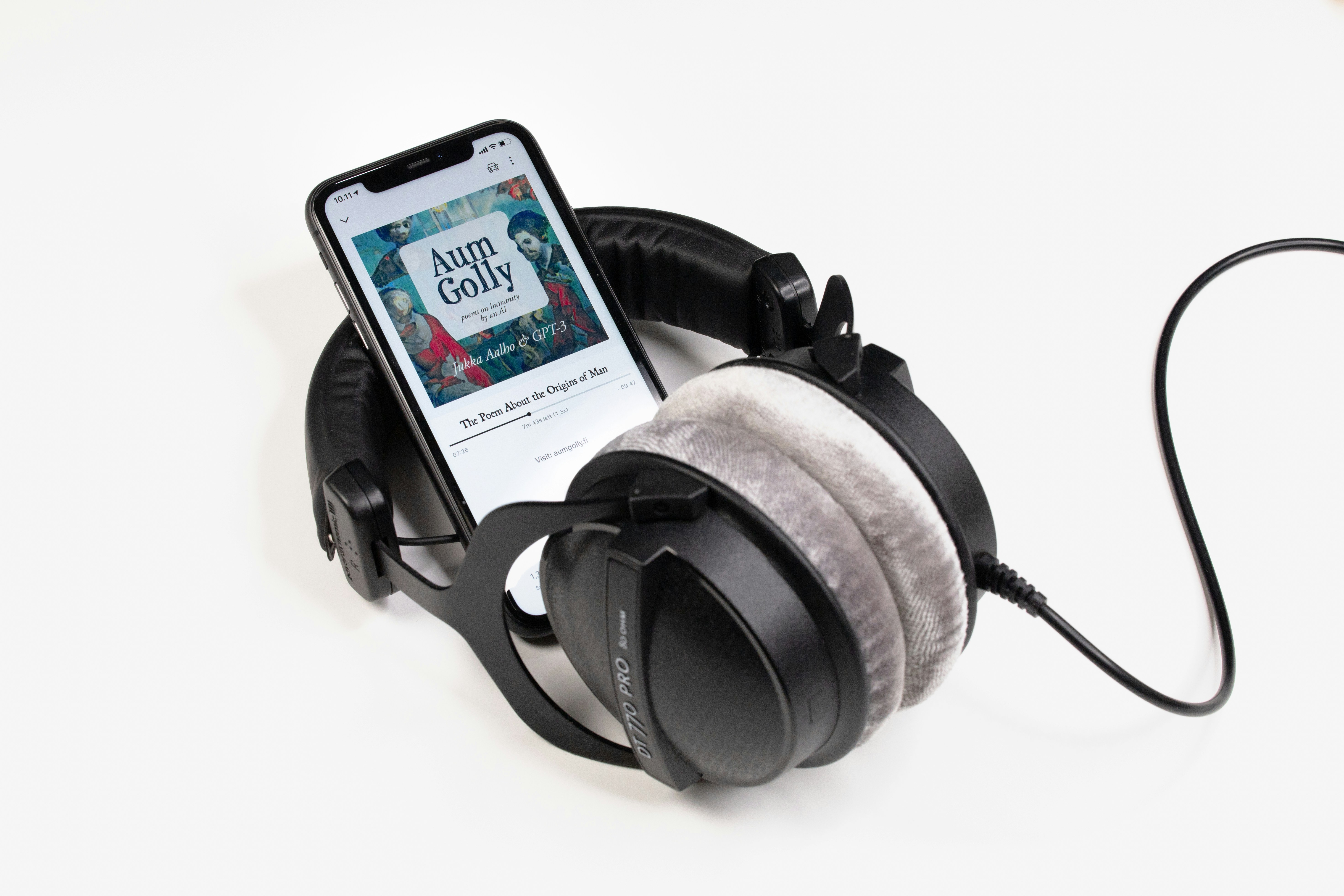 Over-ear headphones beside a smartphone displaying an audiobook.