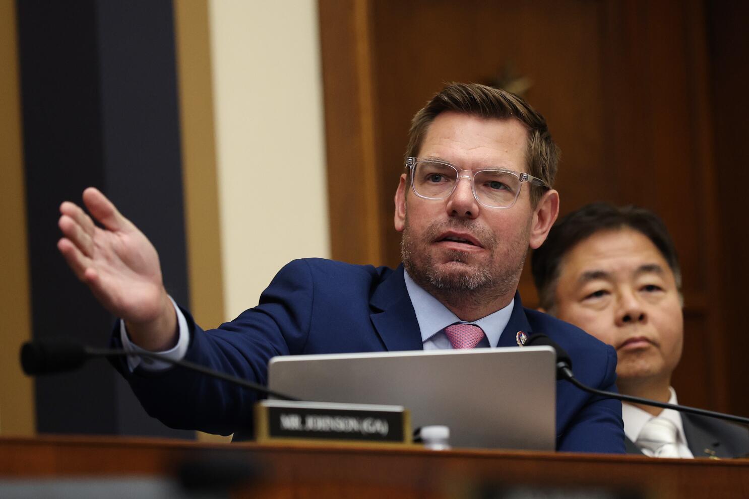 Eric Swalwell speaks and gestures from a seat at a government hearing.