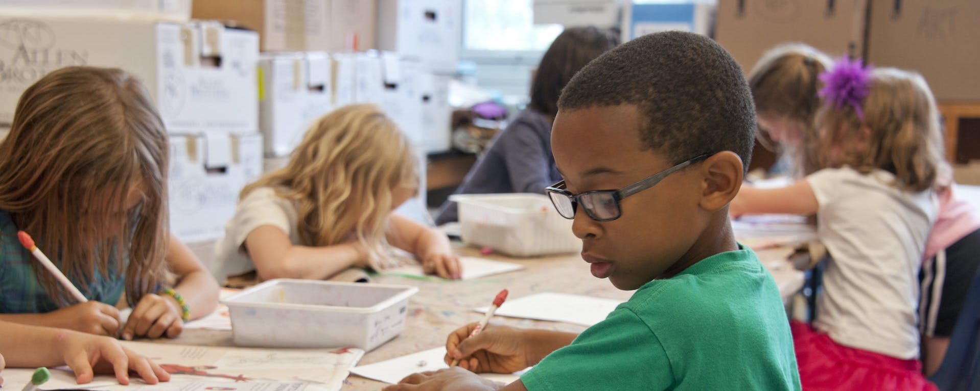 Child writing at desk in classroom