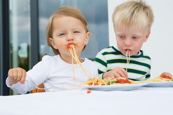 2 kids eating spaghetti
