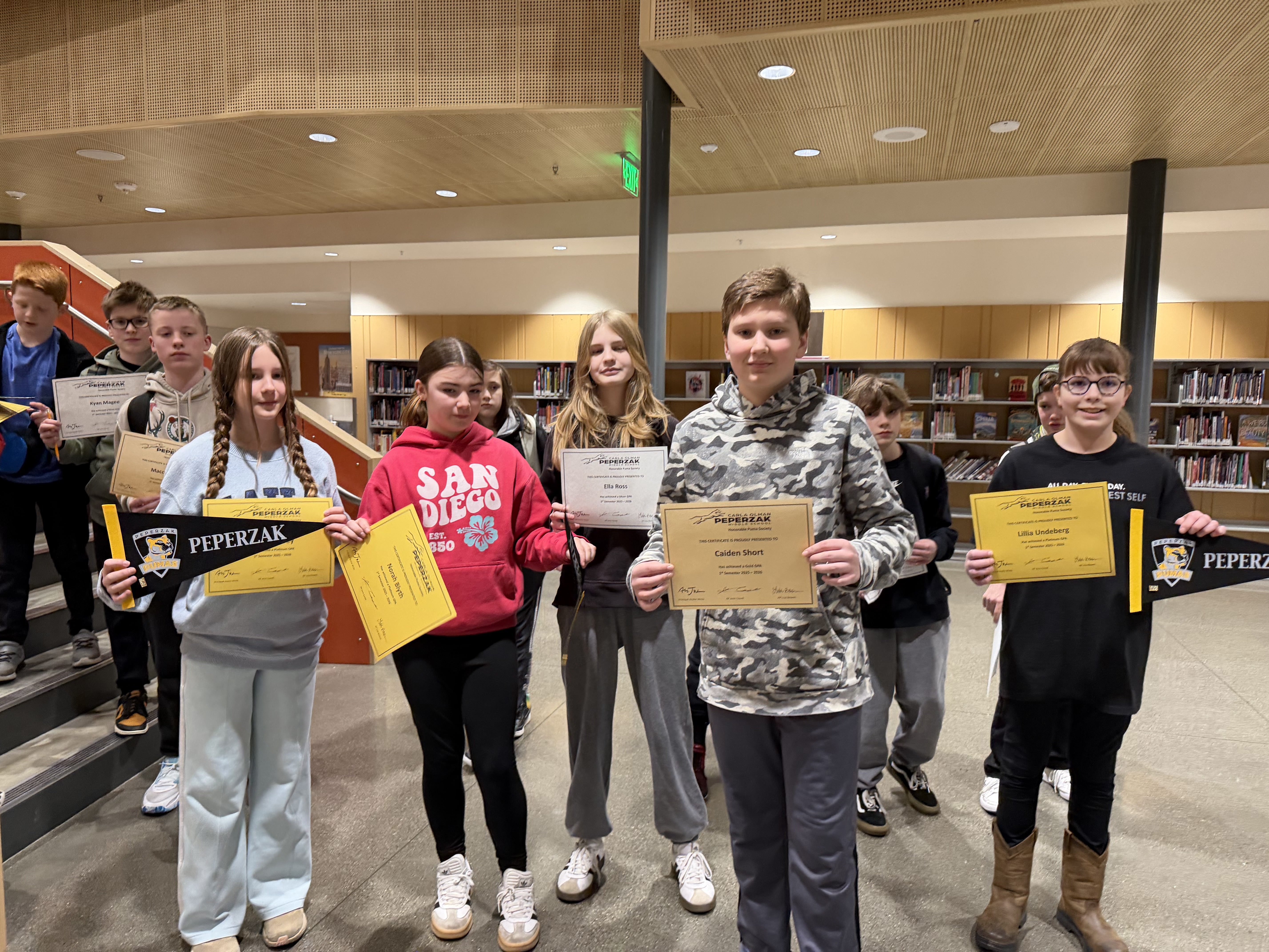 students in front of library books holding pennants and certificates
