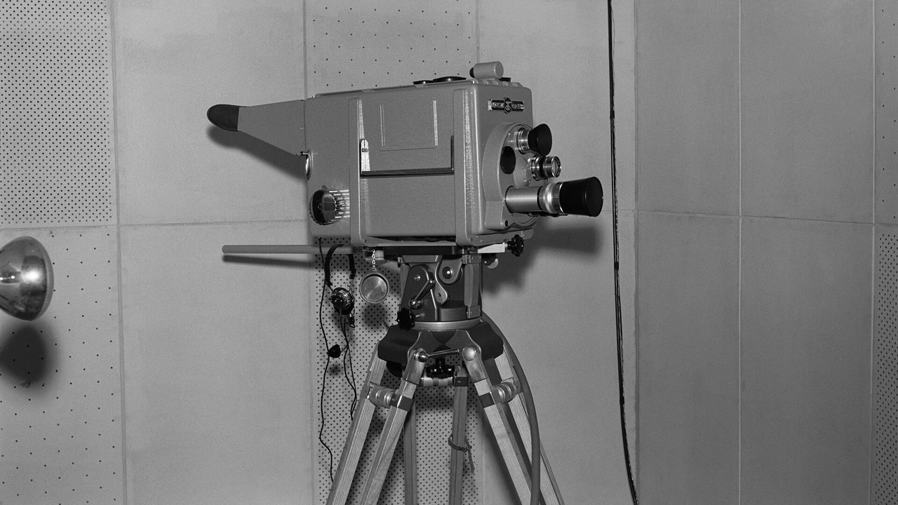 An old television studio camera on a tripod, in a black-and-white photograph