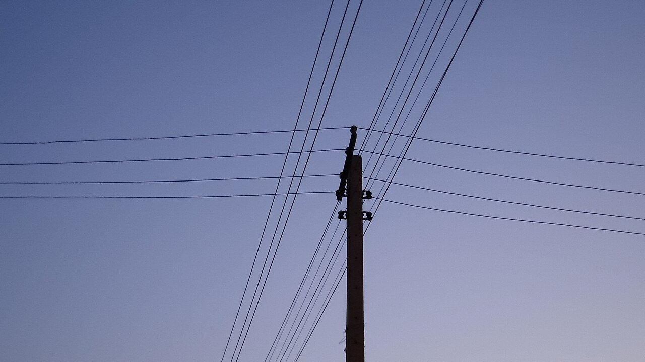 Overhead power lines and a utility pole against a dusk sky.
