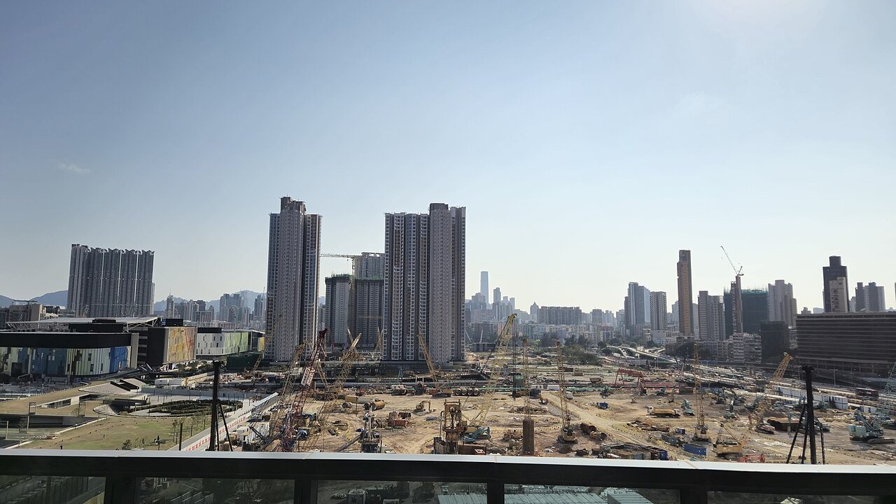 A large residential construction site with cranes and several high-rise housing towers under construction in the background.