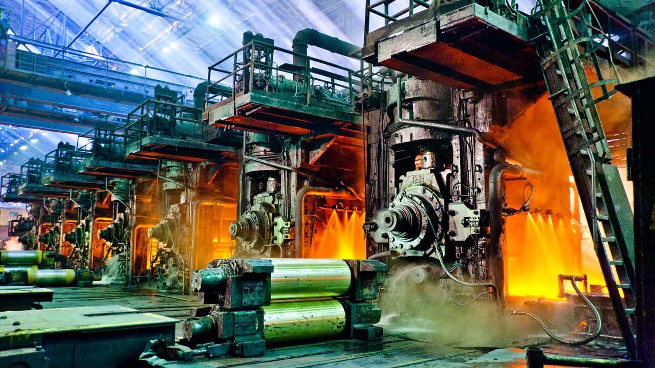 A steel rolling mill with glowing hot metal and rollers in an industrial plant