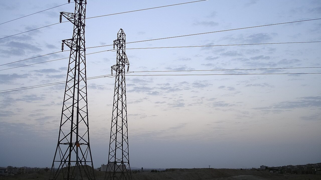 Two steel lattice transmission towers carrying overhead power lines against an evening sky