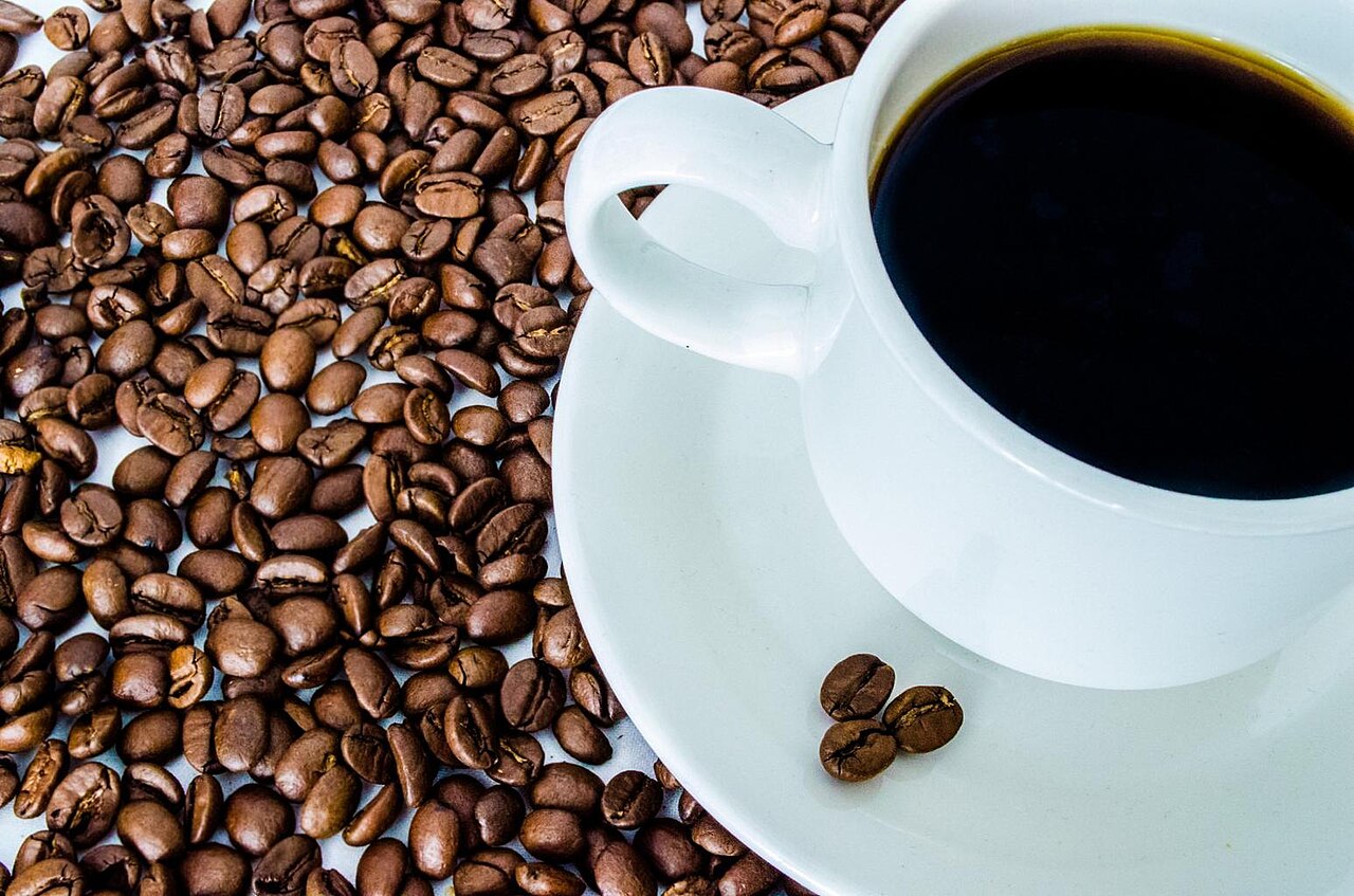 A cup of coffee surrounded by coffee beans