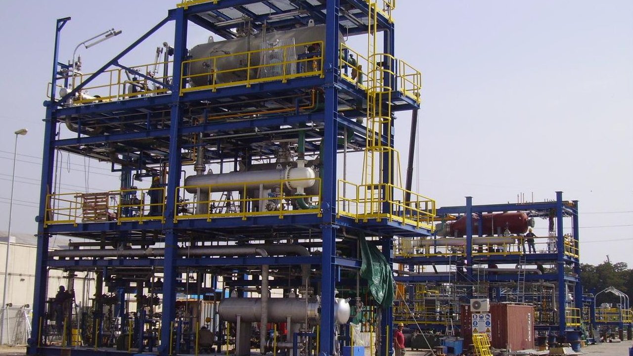 A blue steel framework of chemical process vessels, pipes and walkways at an industrial plant