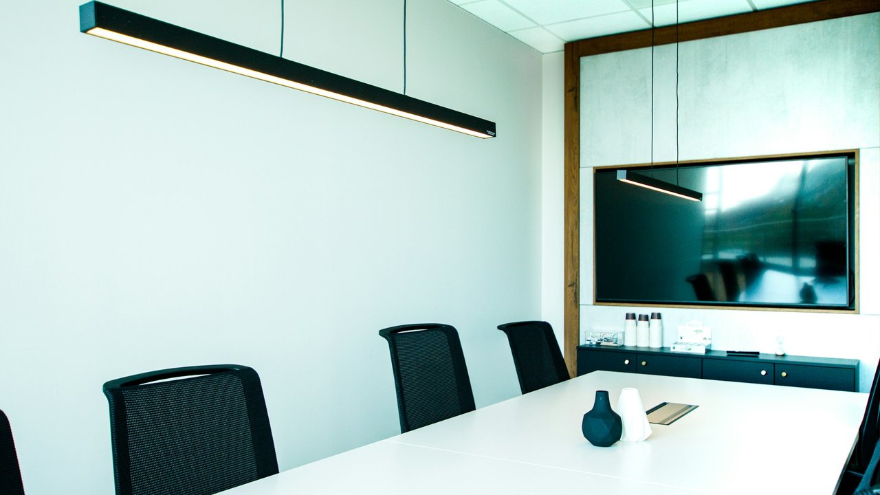 An empty conference room with a white table and black chairs.