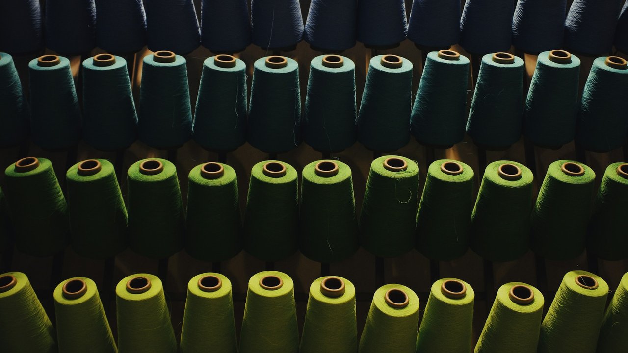 Rows of green and blue yarn cones.