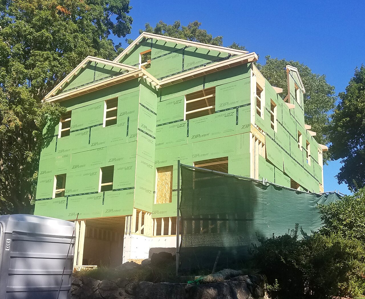 A house under construction wrapped in green sheathing
