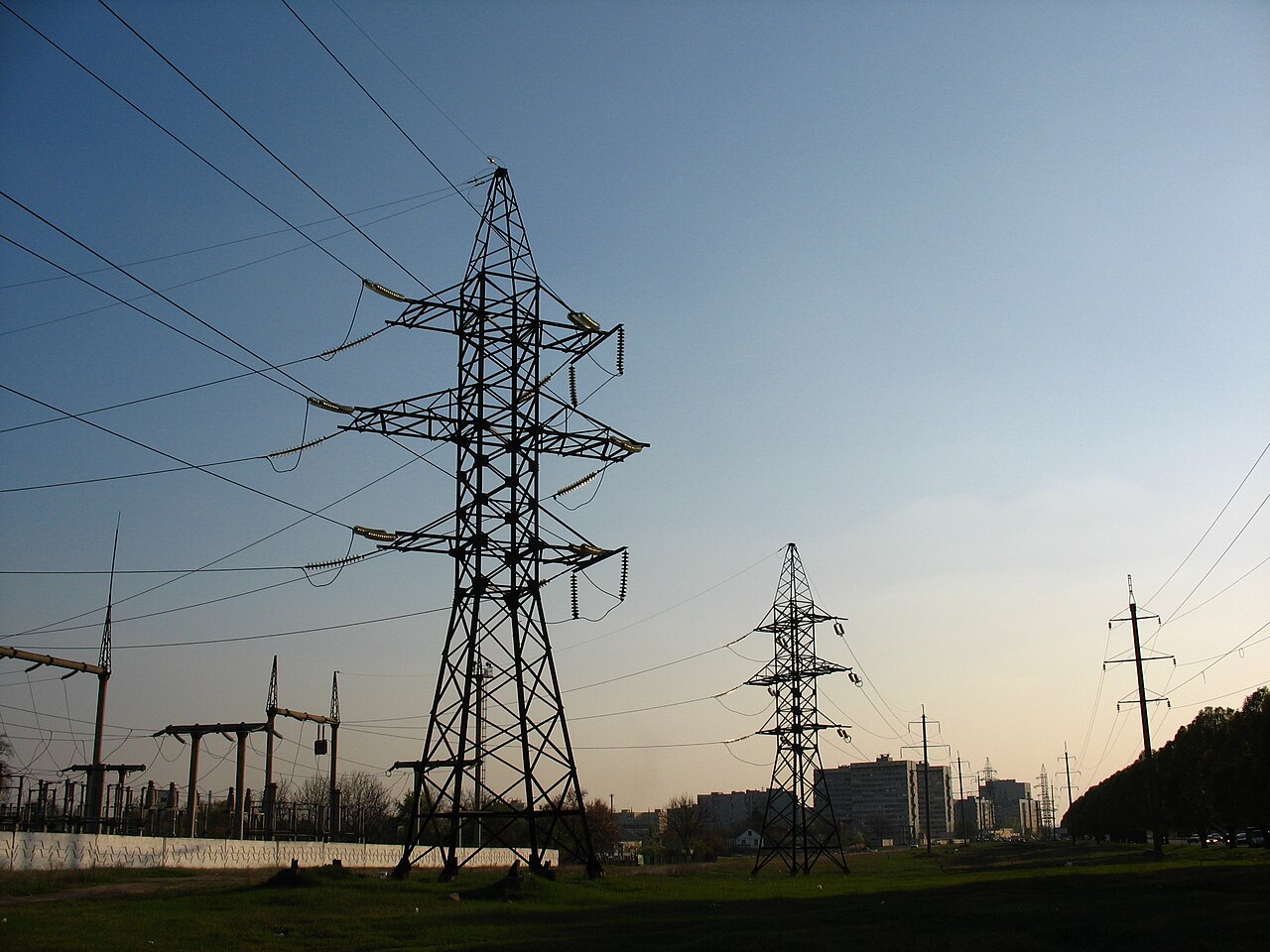 Steel transmission towers and power lines against an evening sky
