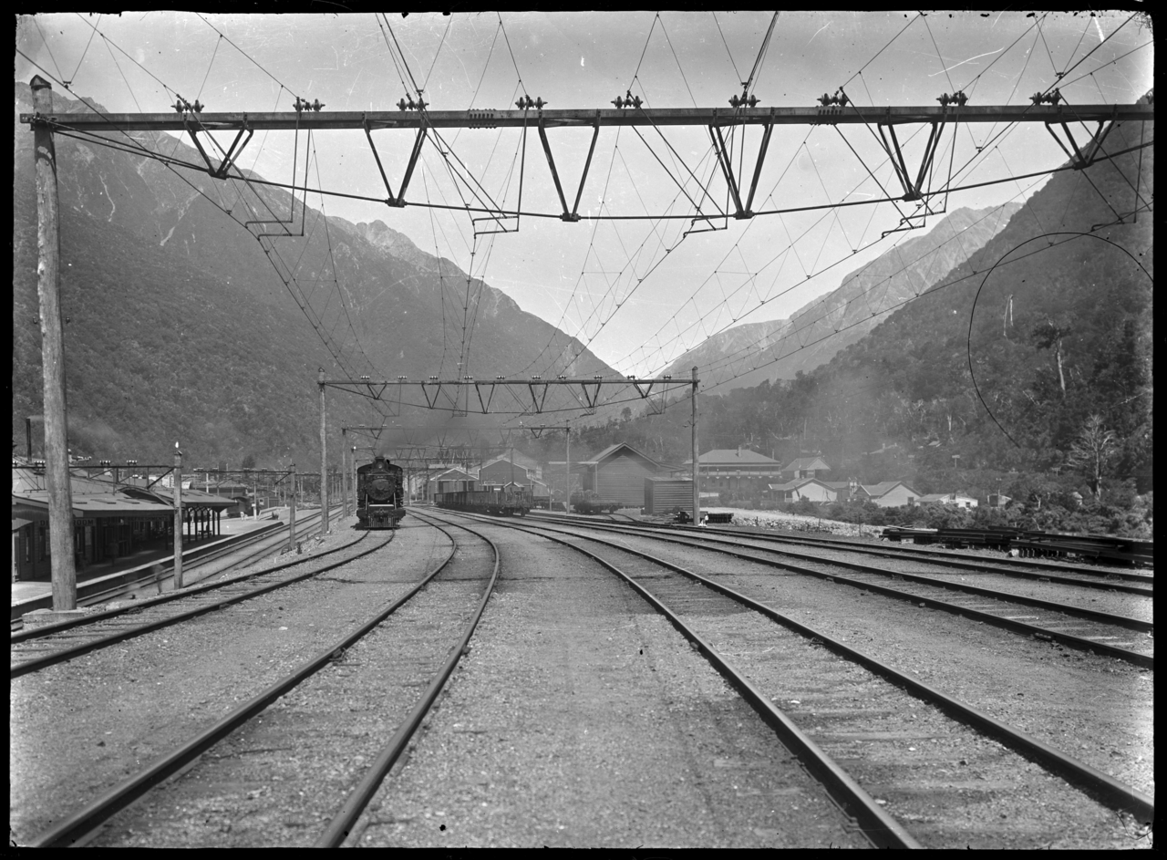 Railway station tracks with overhead electric wires in a mountain valley