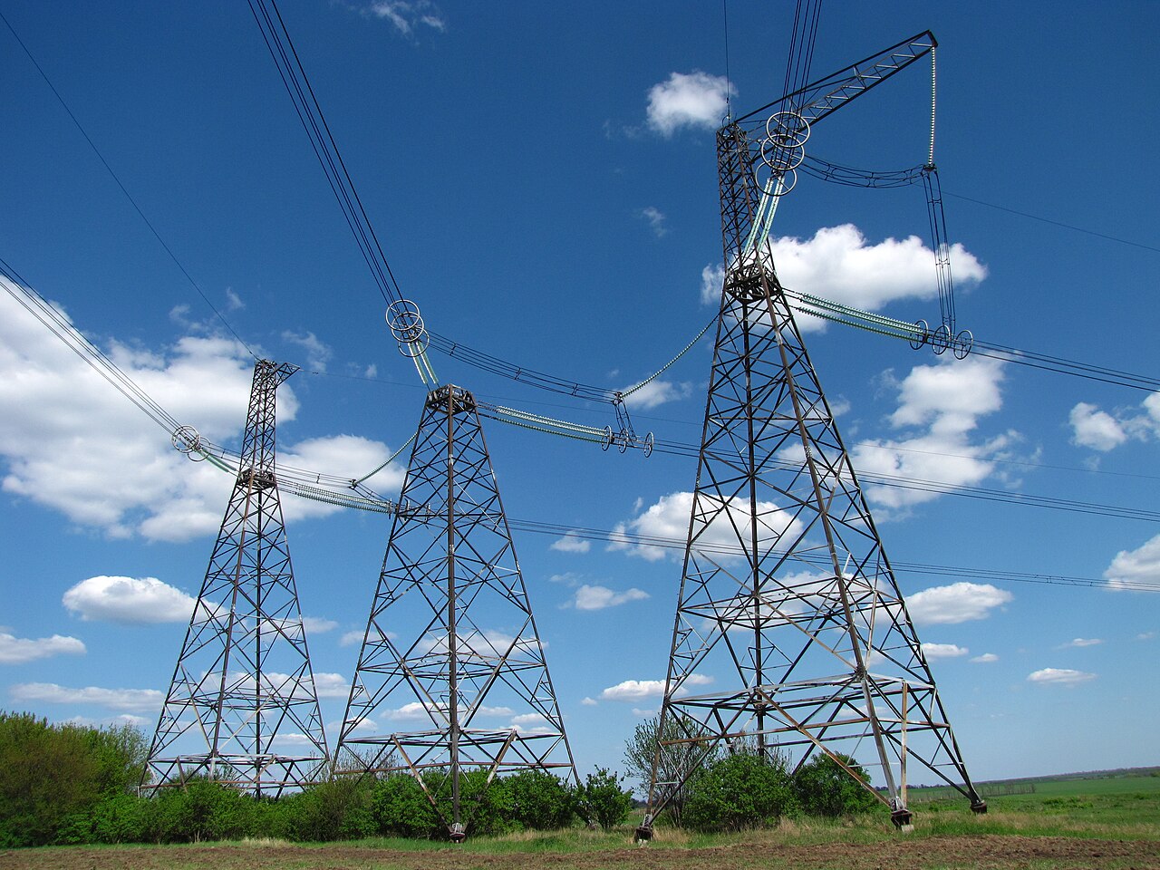 High-voltage transmission towers and overhead power lines under a blue sky