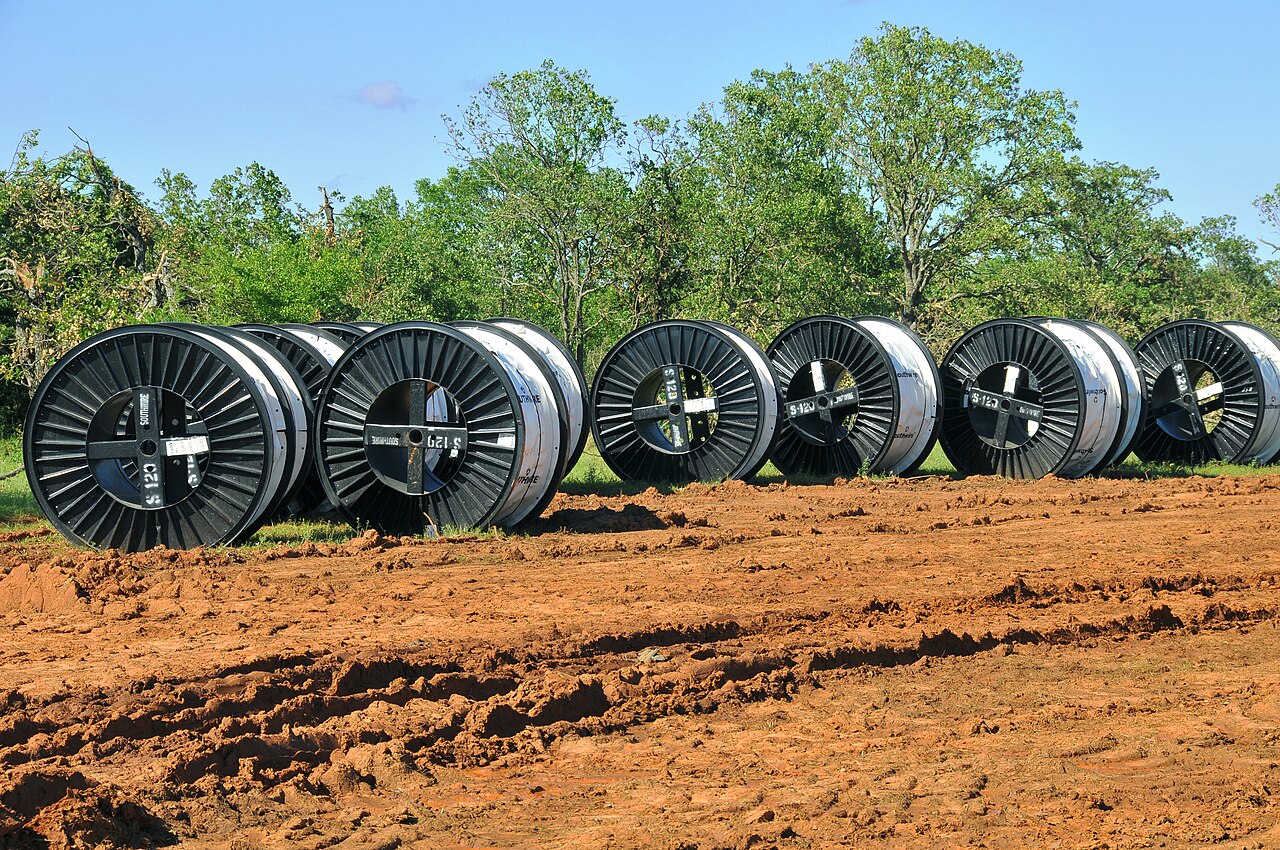 Large reels of electrical cable lined up on open ground