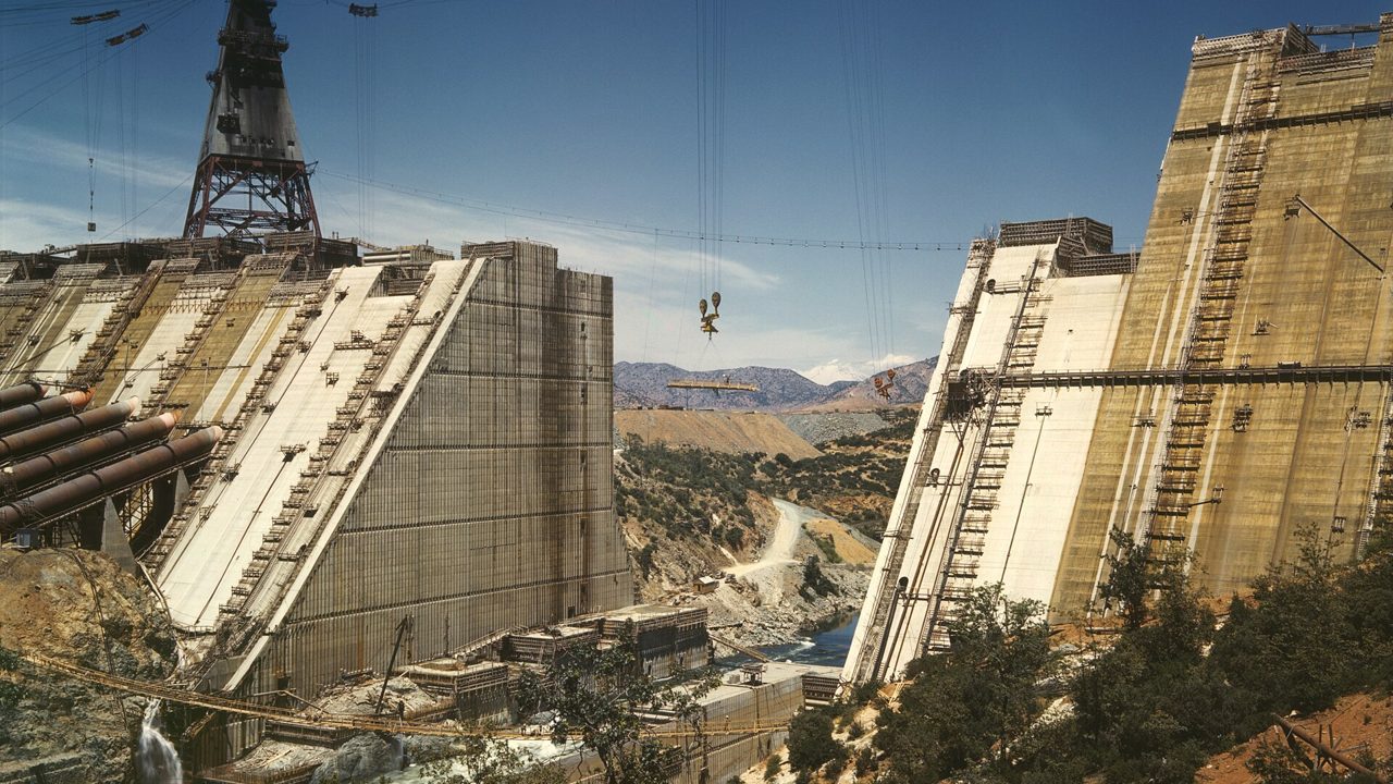 A dam wall under construction in a river valley