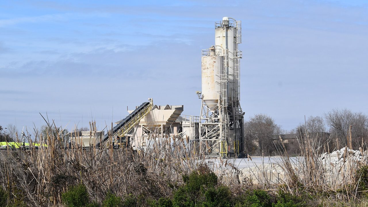 A cement plant with silos and conveyors beside a field