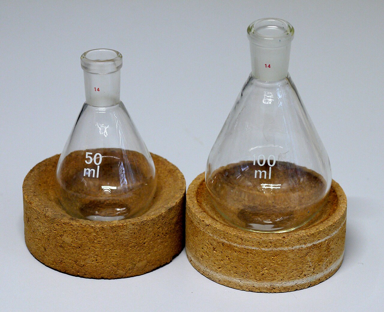 Two glass laboratory flasks standing in cork rings