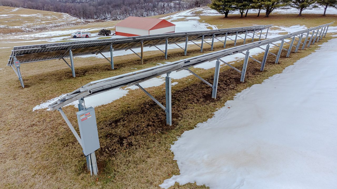 Rows of ground-mounted solar panels beside a field