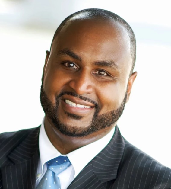 Dr. Raymond Marbury Jr., smiling in a pinstripe suit