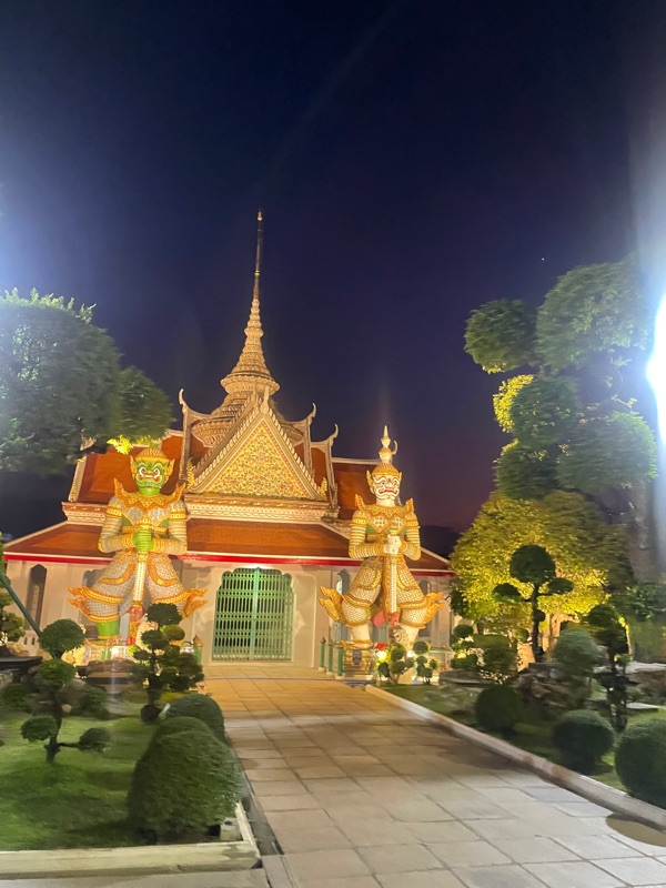 Wat Arun Temple entrance at night in Bangkok Yai, Thailand with green and white yaksha guardians