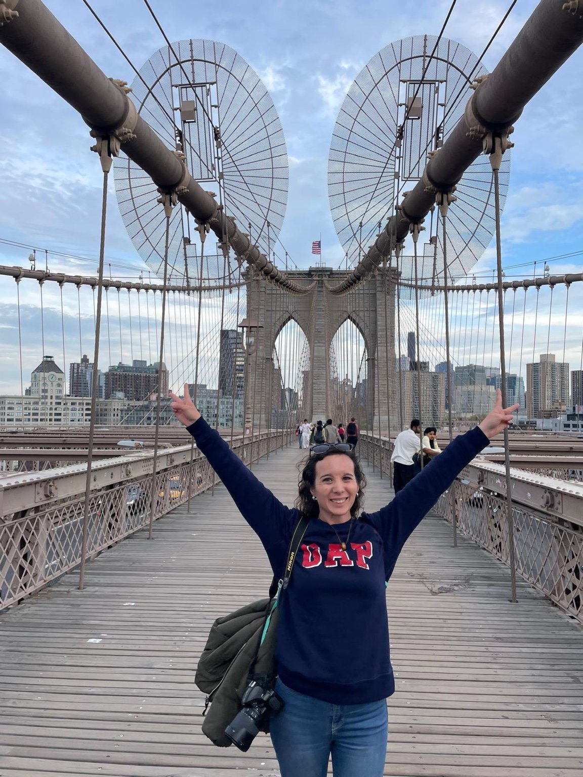 Posando con los brazos en alto sobre el puente de Brooklyn con los arcos alineados