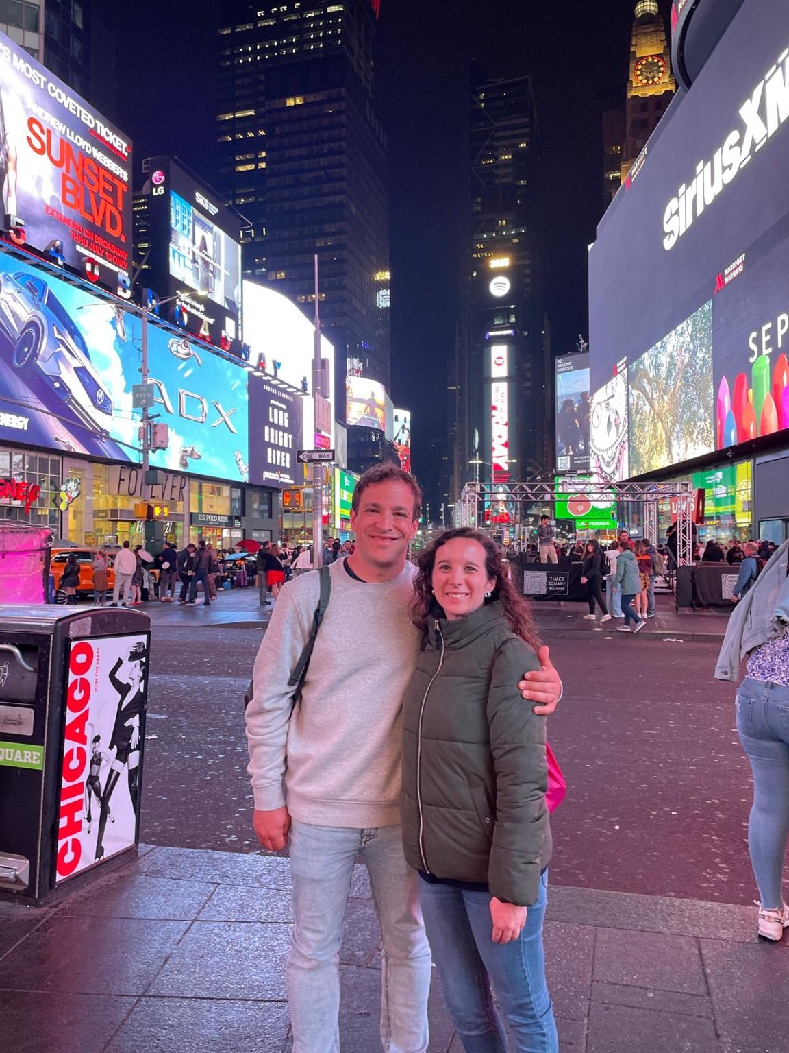 Pareja en Times Square de noche rodeada de pantallas LED