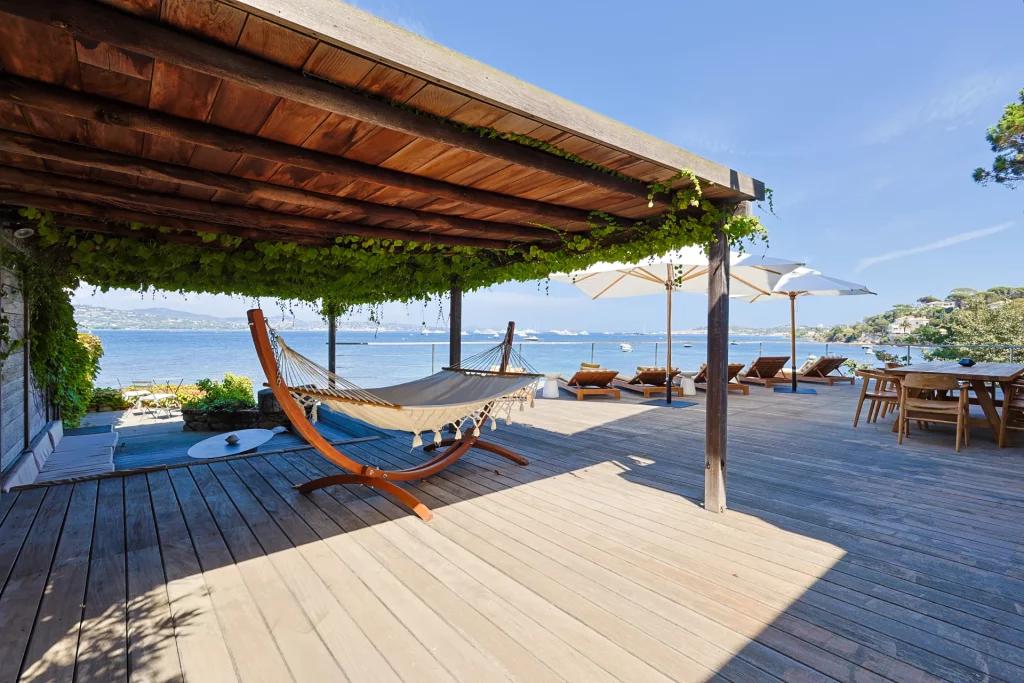 Saint-Barthelemy accommodation - La Tortue - Wooden terrace with a hammock, umbrellas, and dining table, offering a stunning view of the sea.