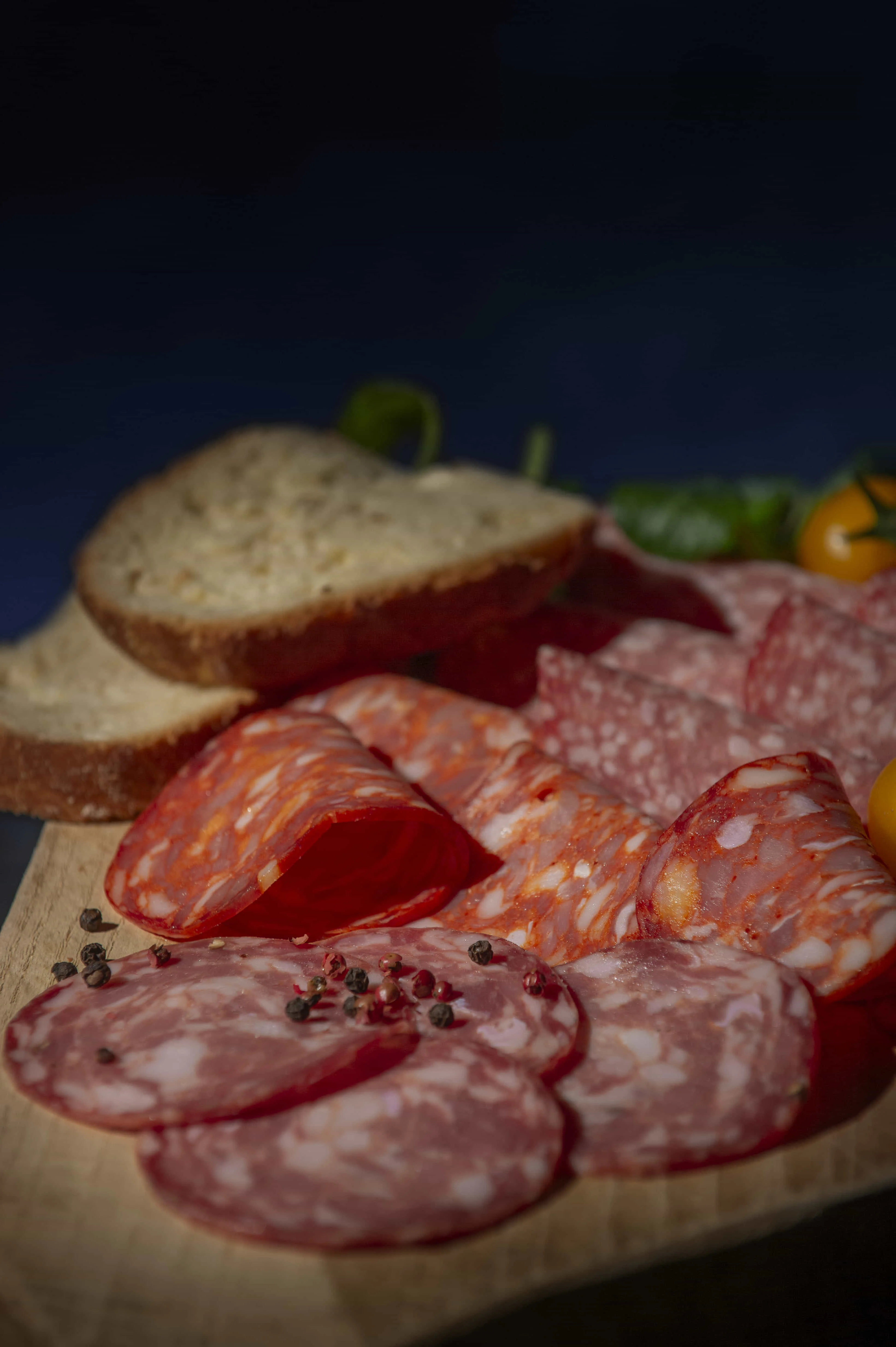 Tagliere in primo piano con salumi Bombieri tagliati a fette e pane in accompagnamento