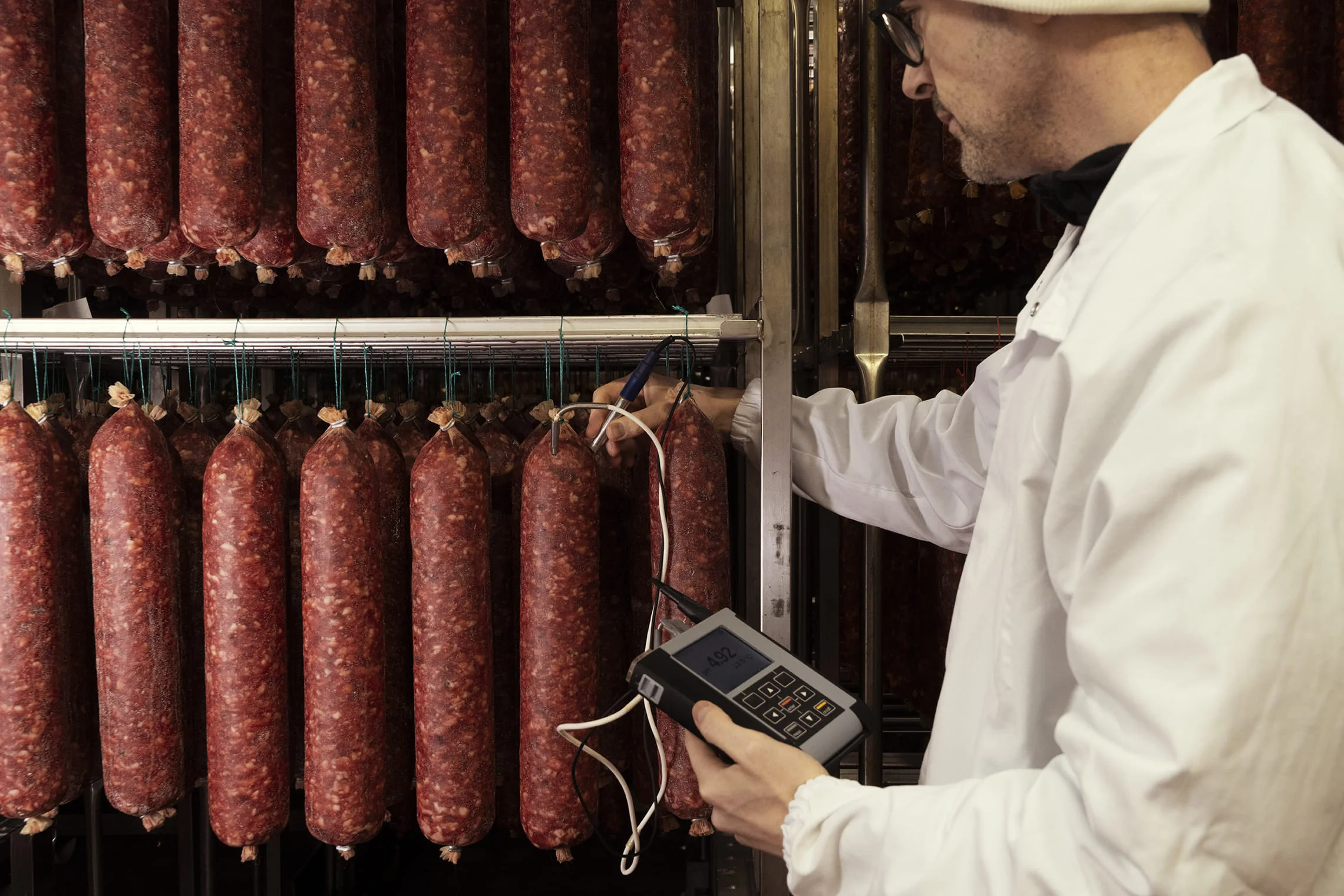 Dipendente che effettua il controllo qualità su dei salami