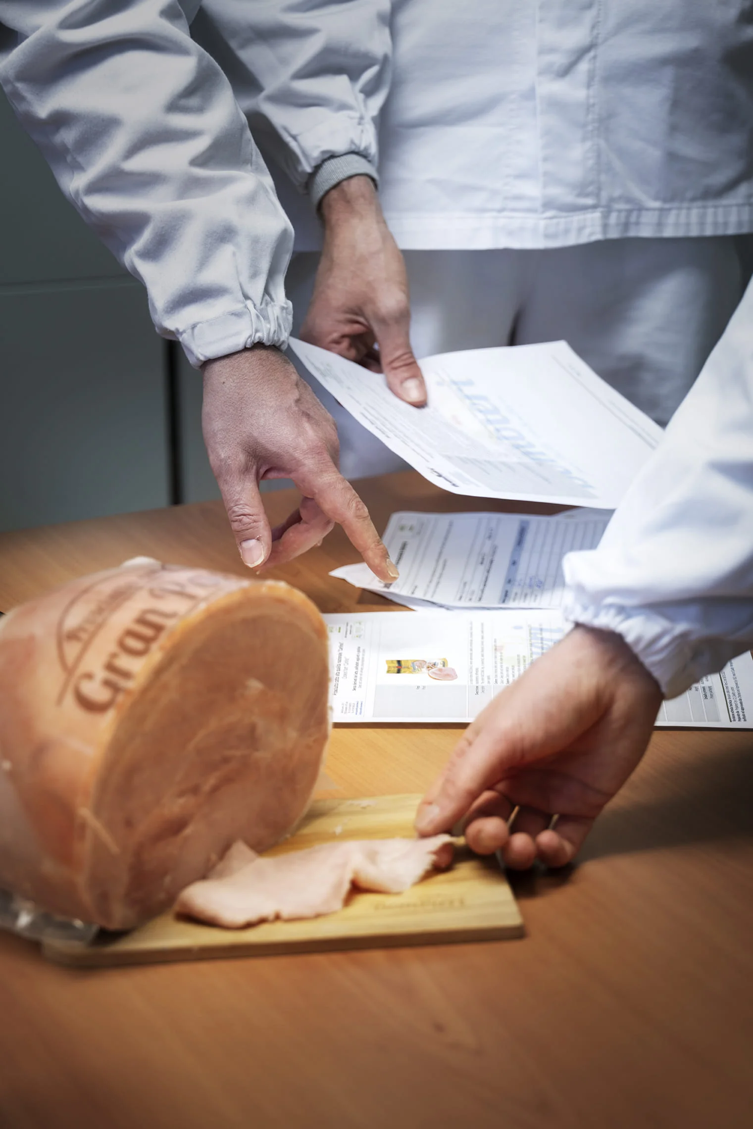 Employees' hands performing quality control and analyzing paper data from the analysis