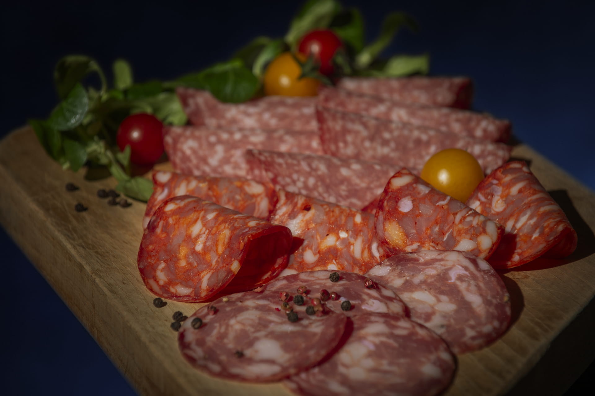 A rich platter of cured meats and cherry tomatoes, enhanced with pepper. The perfect appetizer!