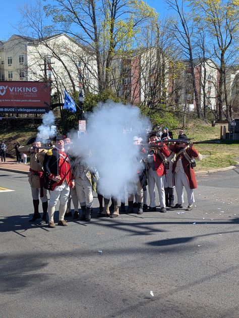 A line of soldiers unleashes a volley — smoke fills the street