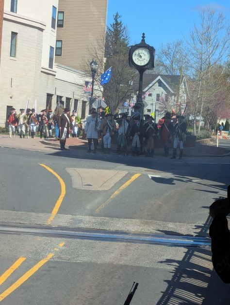 Soldiers in formation along Main Street as spectators watch from the sidewalk