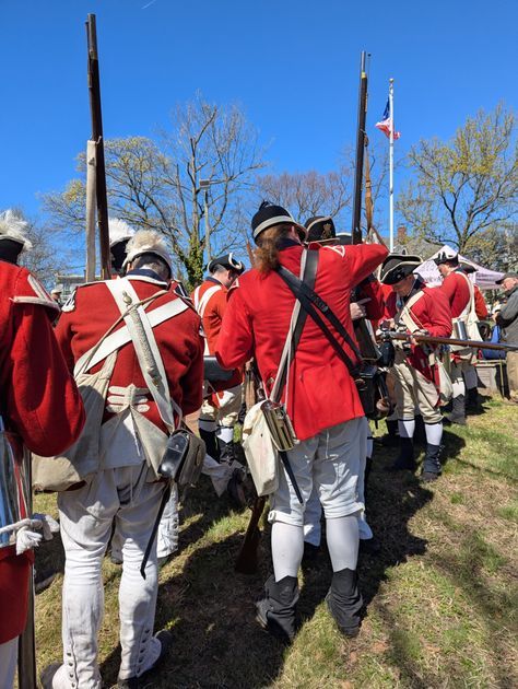 Soldiers stand at attention during the ceremony, a historic building visible behind them