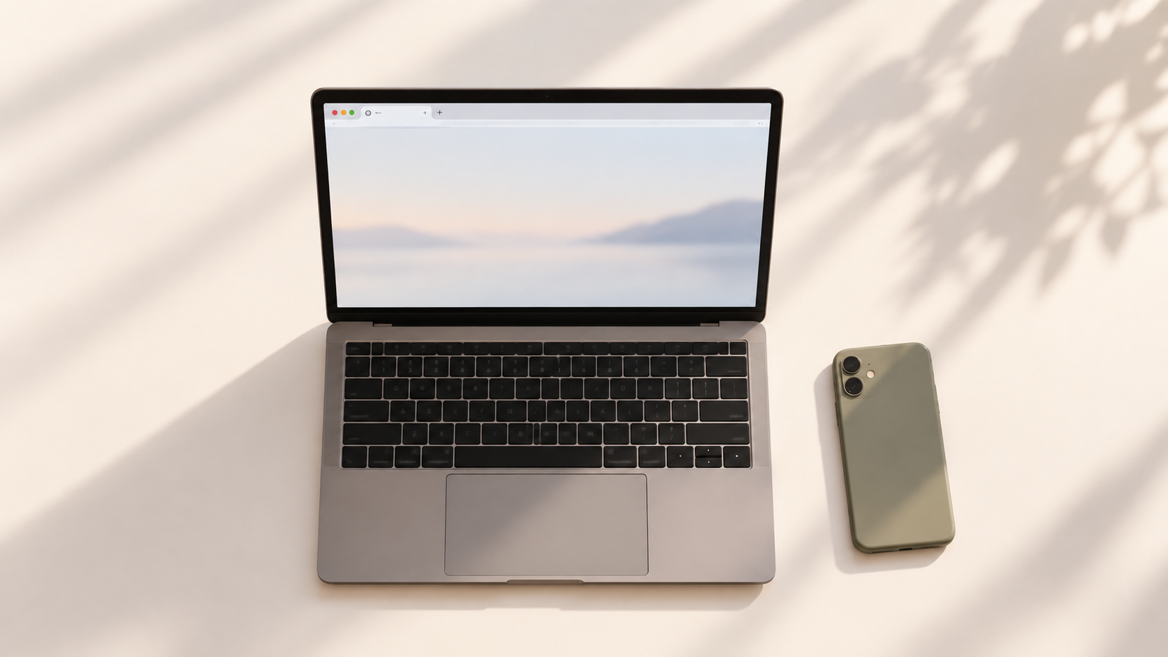 A laptop with a single browser tab open on a clean desk, with a phone placed face-down beside it, representing calm, single-stream focus.