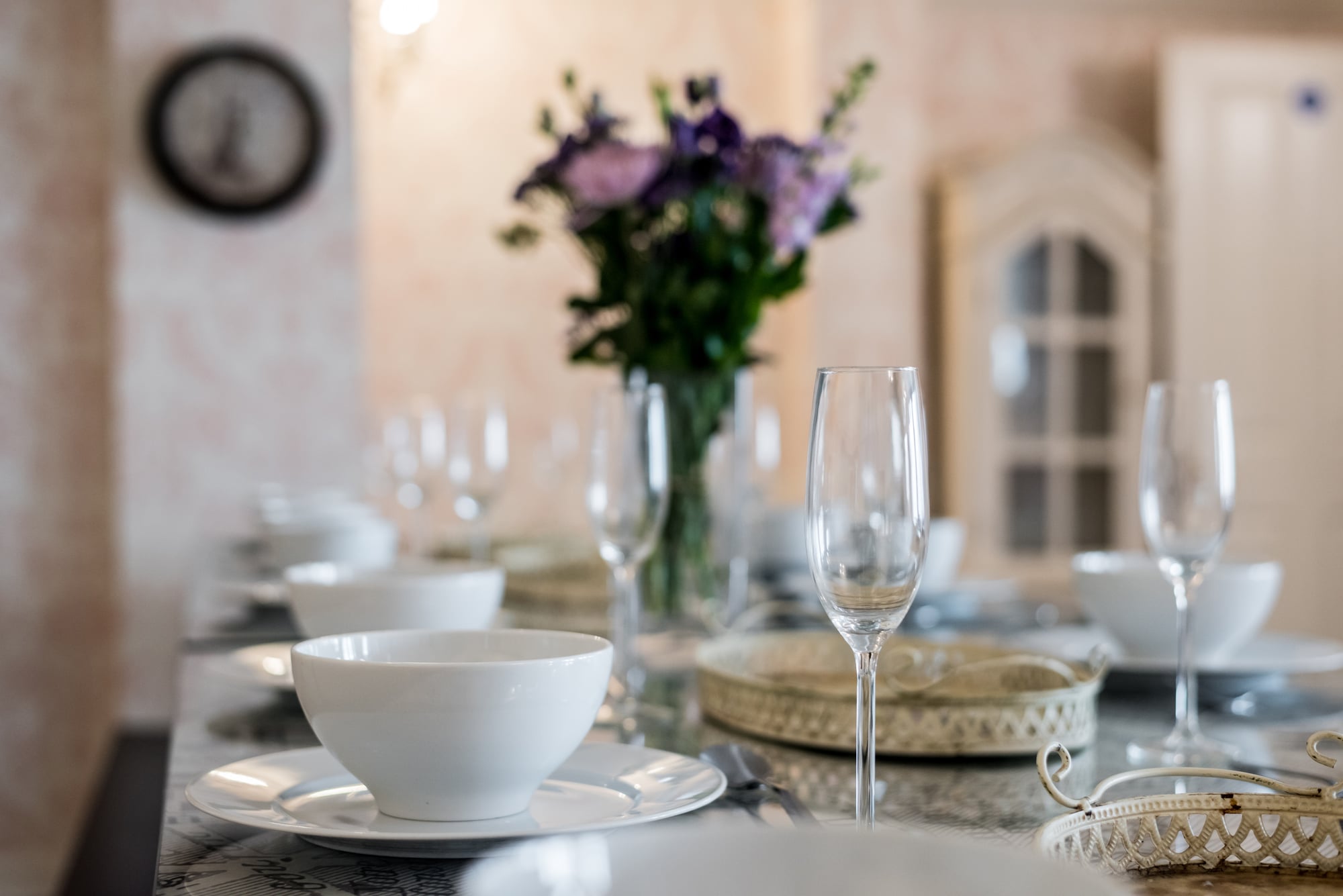 A long dining table laid for the whole group, with champagne flutes, white place settings and fresh flowers