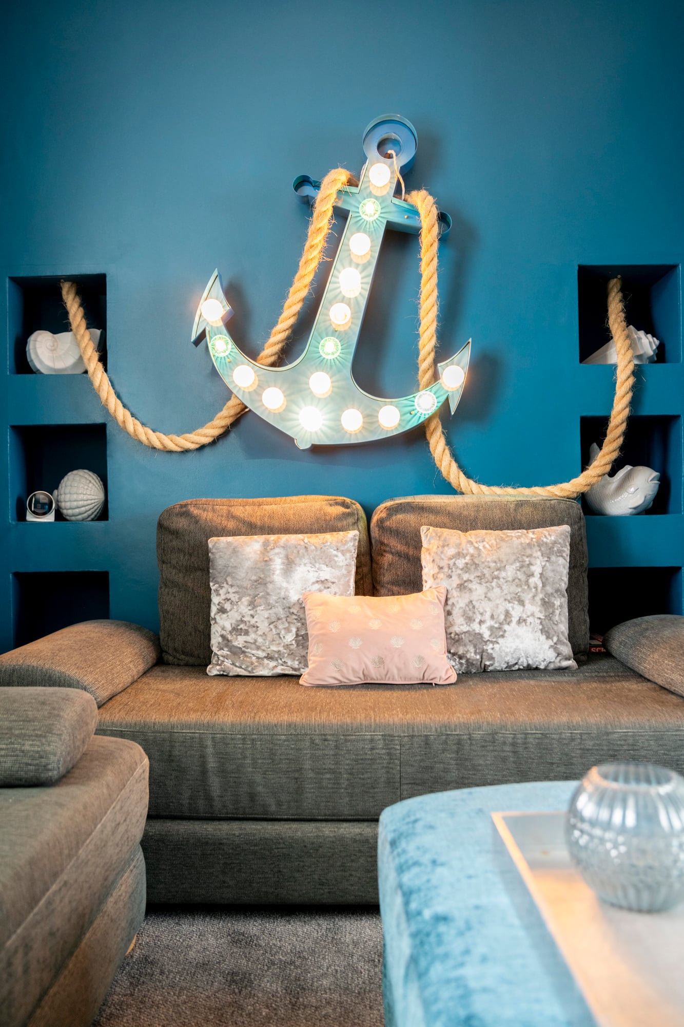 The nautical lounge at Darling By The Sea, with a teal wall and an illuminated anchor light