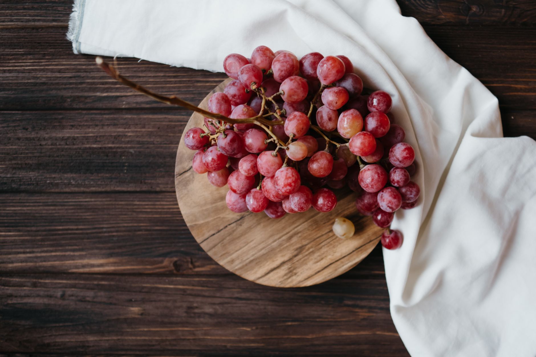 Close-up of a ripe grape on a wooden surface, soft natural light highlighting its smooth skin