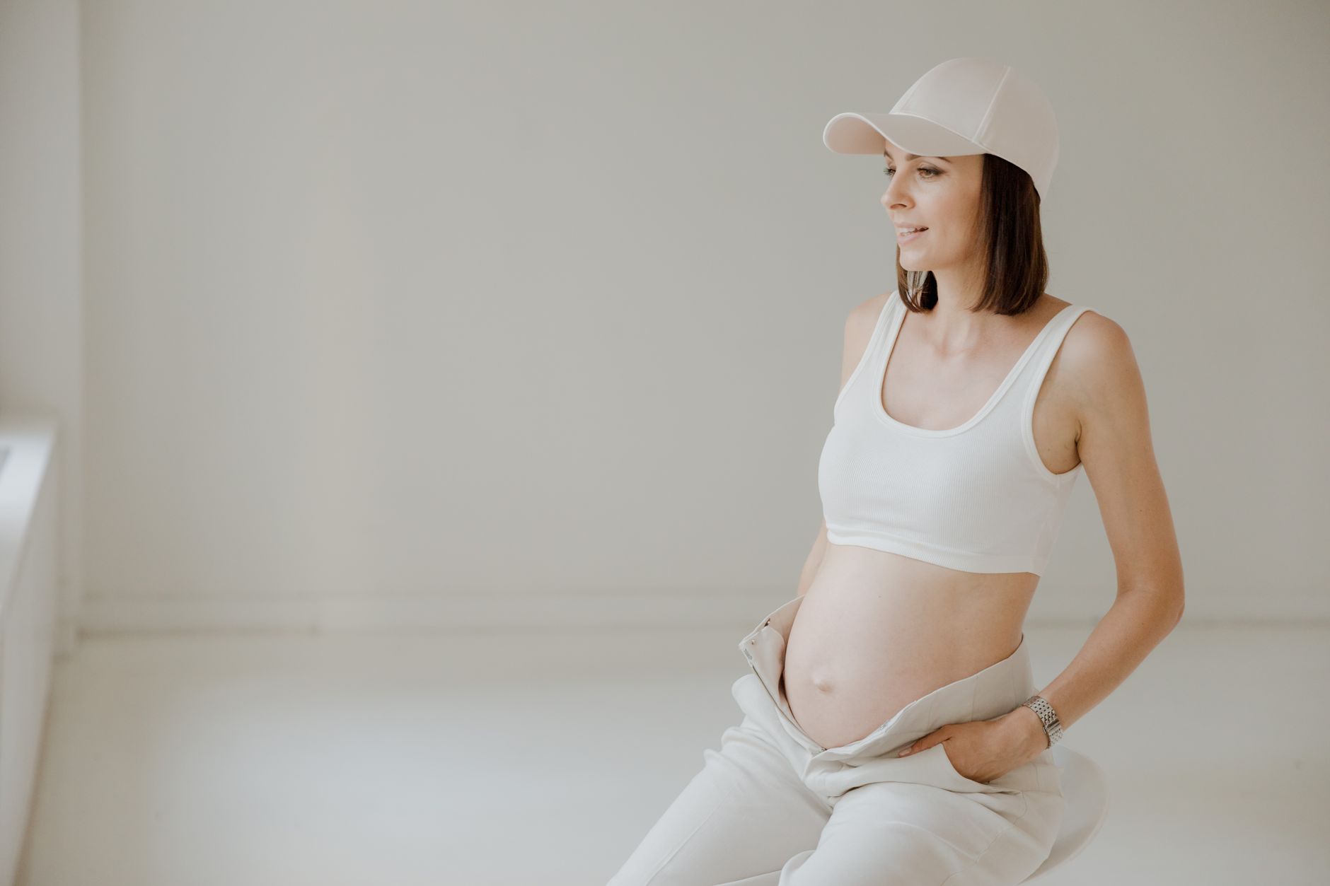 Pregnant woman at 13 weeks wearing a belly band over unbuttoned jeans