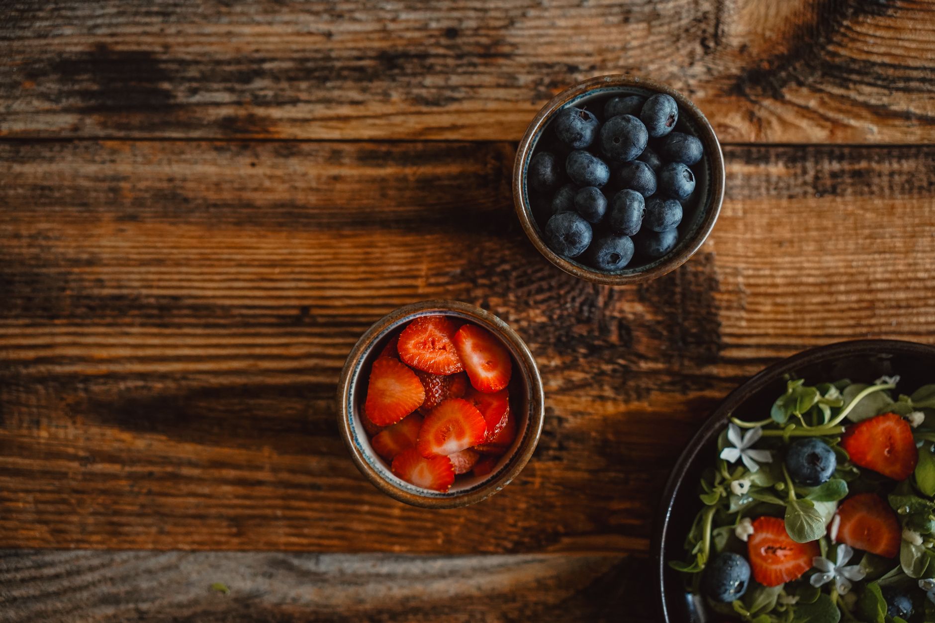 A variety of fresh, colorful fruits and vegetables laid out on a clean wooden table, emphasizing healthy eating
