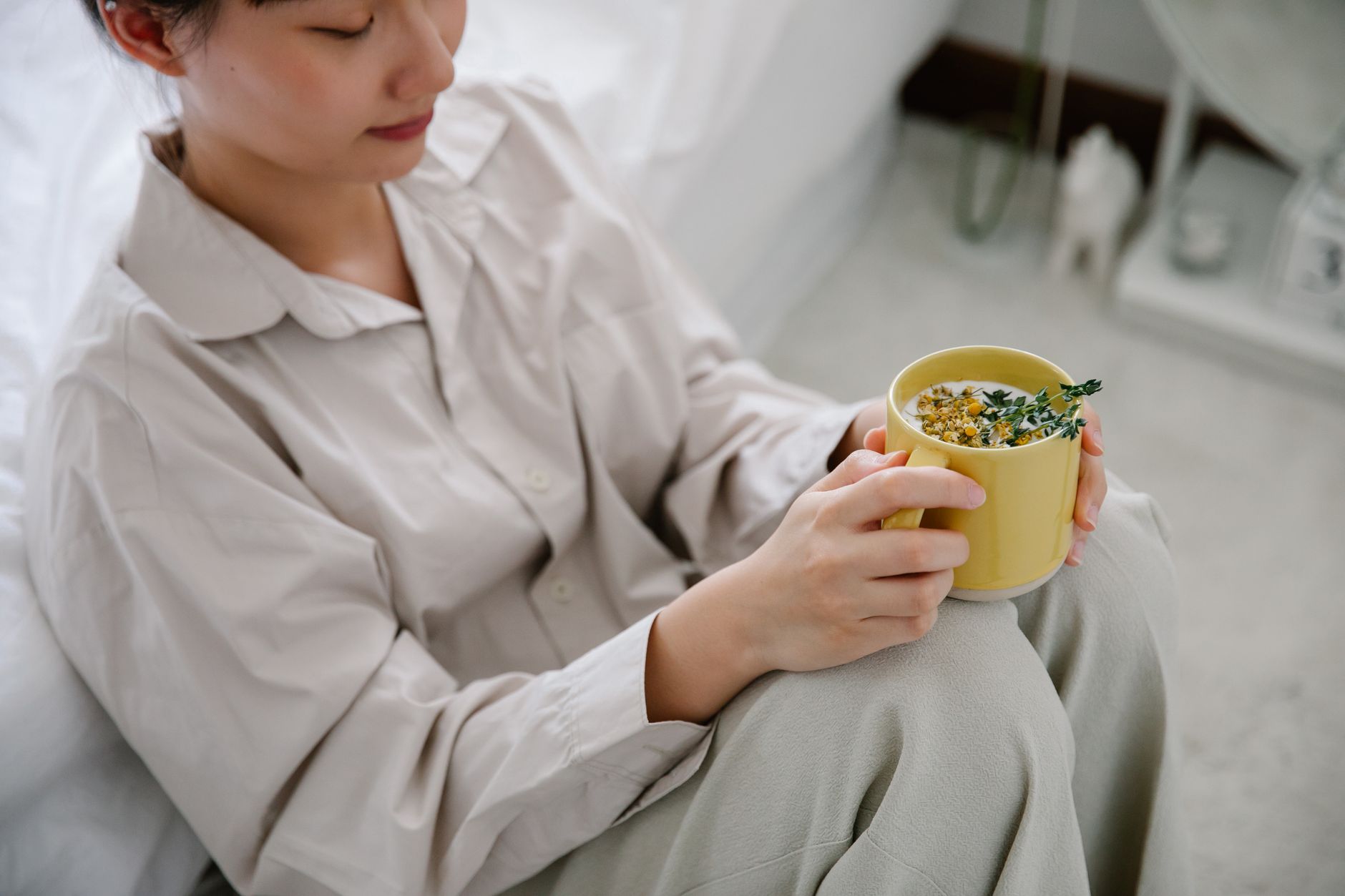 Pregnant woman seated on a cozy couch, sipping herbal tea, with a pillow supporting her back