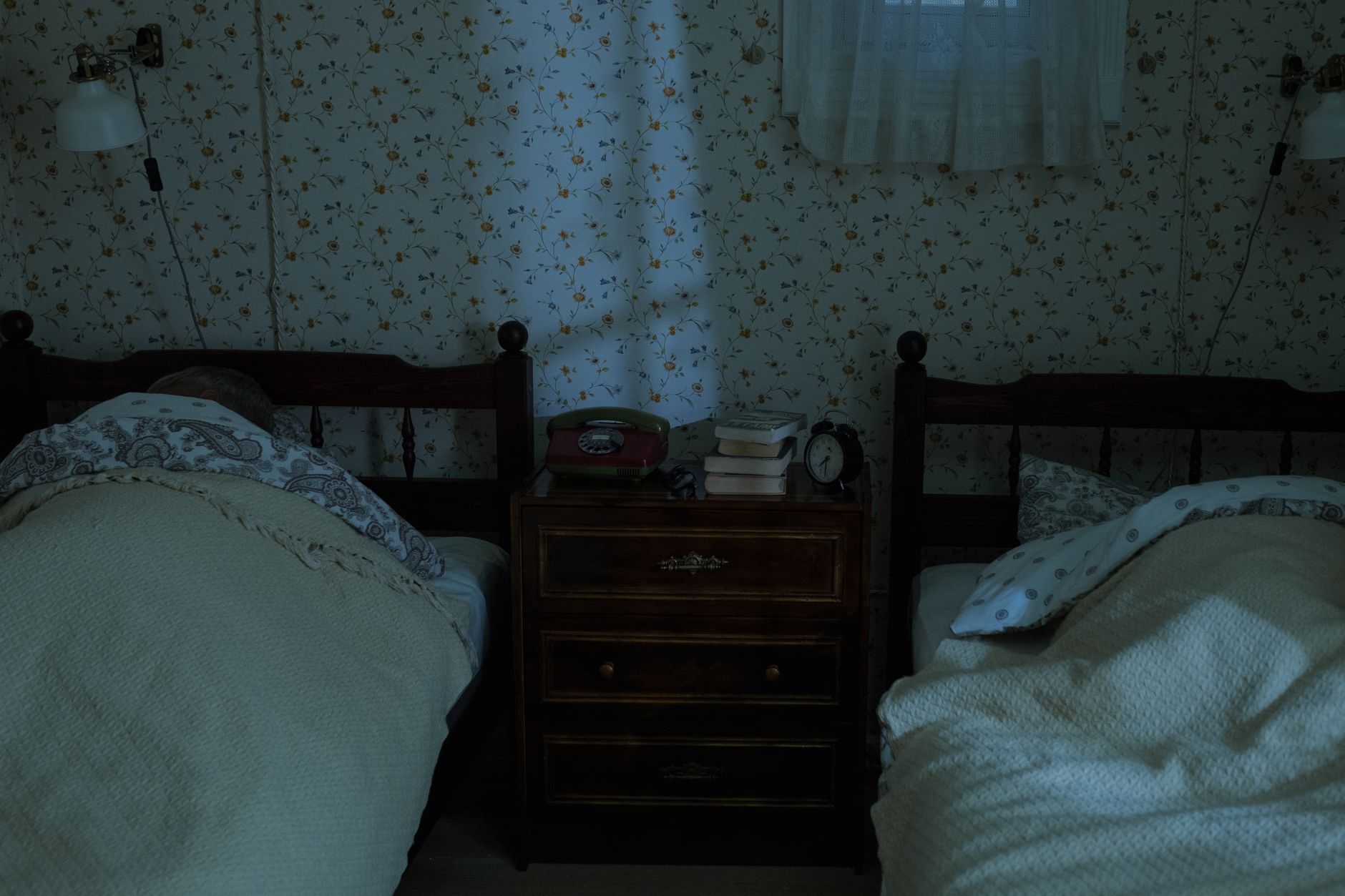 A calm bedroom scene with a pregnant woman sleeping on her side, soft white bedding, a nightstand with a water glass and a small lamp, gentle morning light filtering in