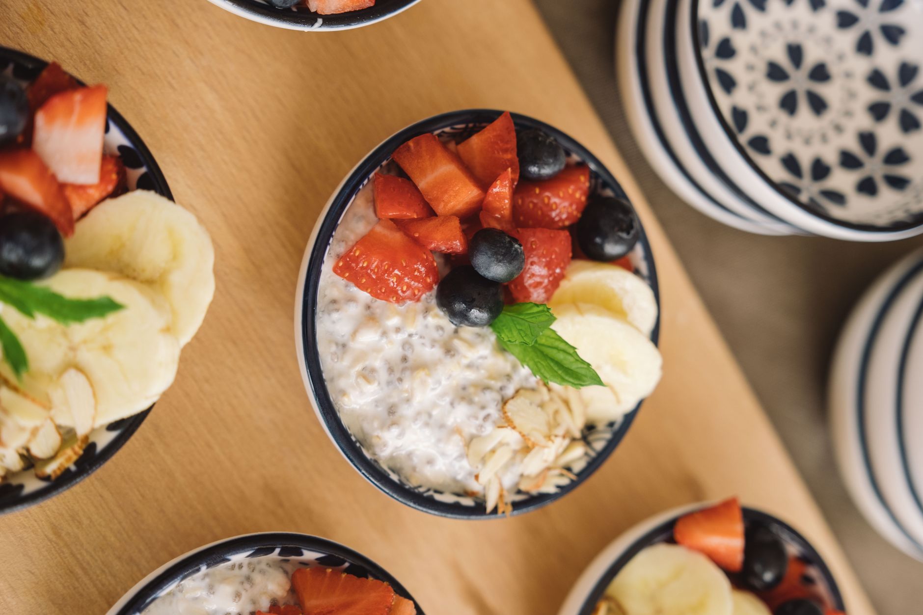 Close‑up of a wooden board with a bowl of oatmeal, sliced bananas, almonds, and a glass of water, bright natural light highlighting the healthy breakfast for a pregnant woman