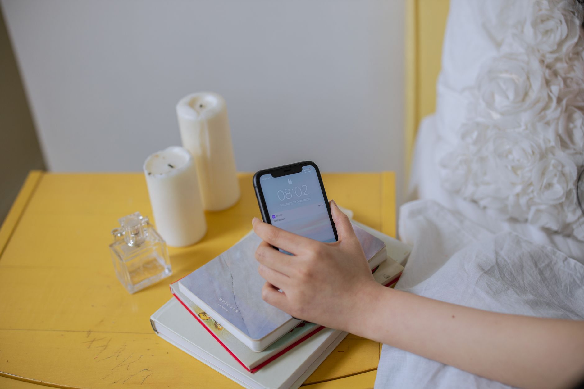 A pregnant woman's hand reaching for a phone on a bedside table, suggesting she needs to call for medical advice, soft lighting