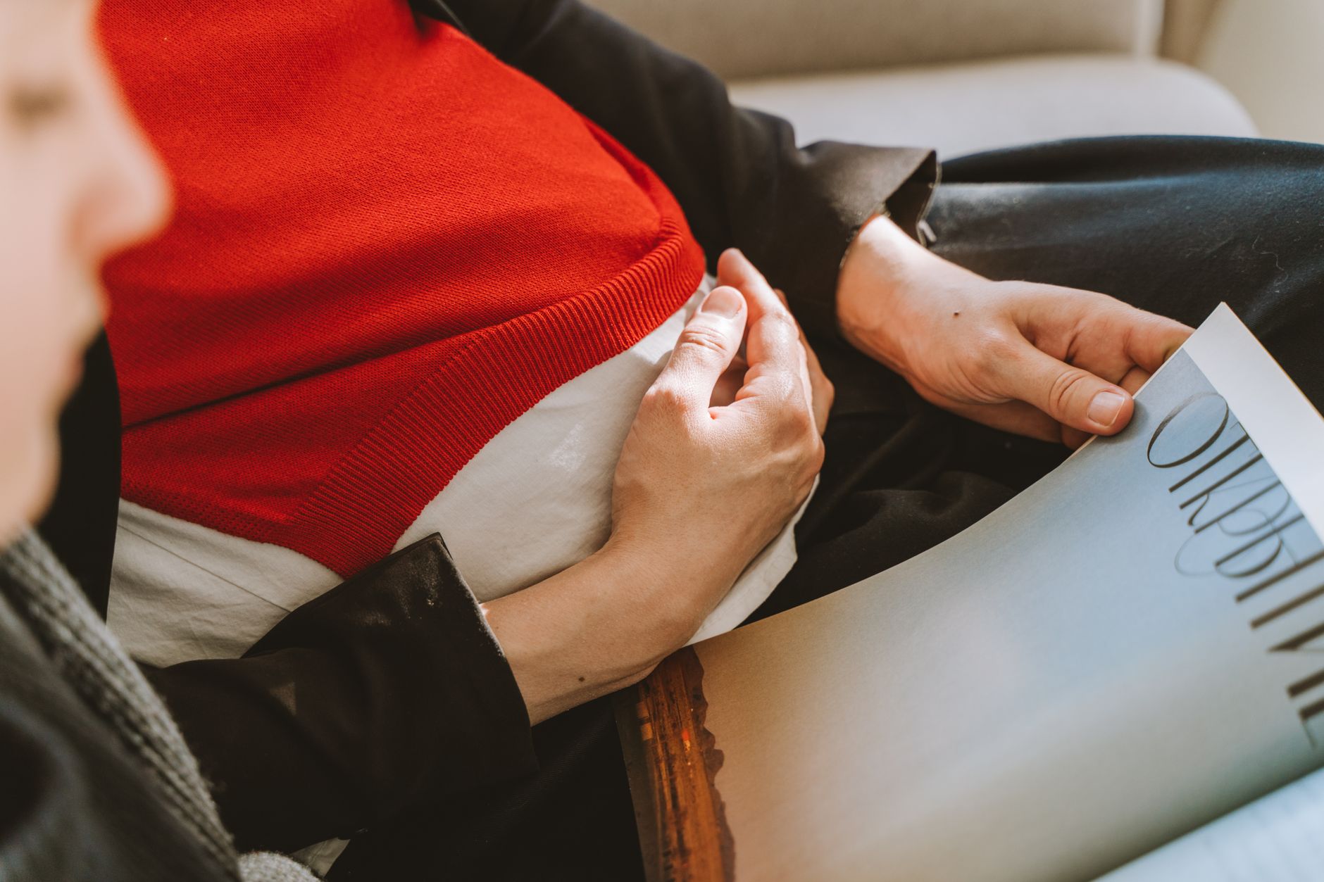 A smartphone displaying a contraction timer app, with hands gently resting on a pregnant belly in the background
