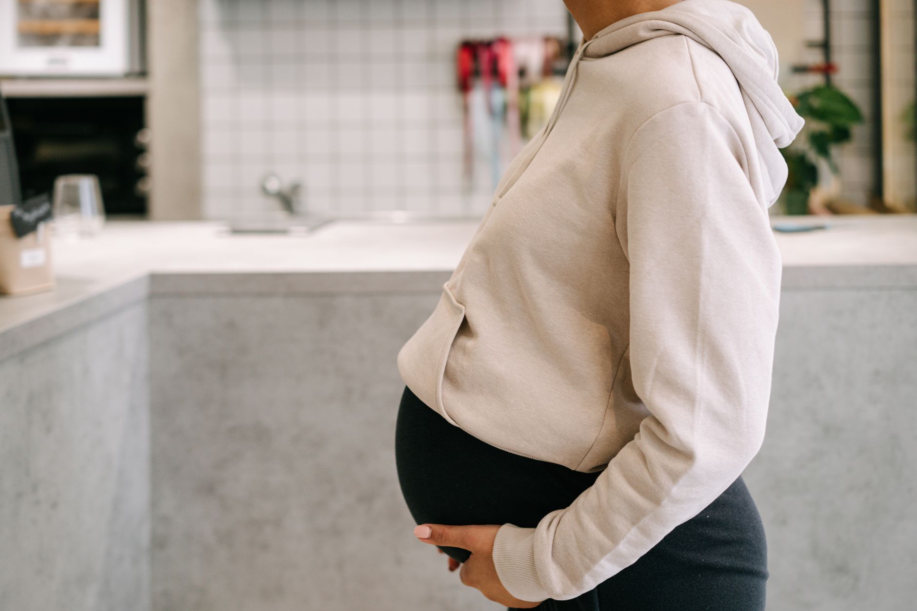 Pregnant woman wearing a loose shirt, sitting comfortably with a glass of water before her ultrasound appointment