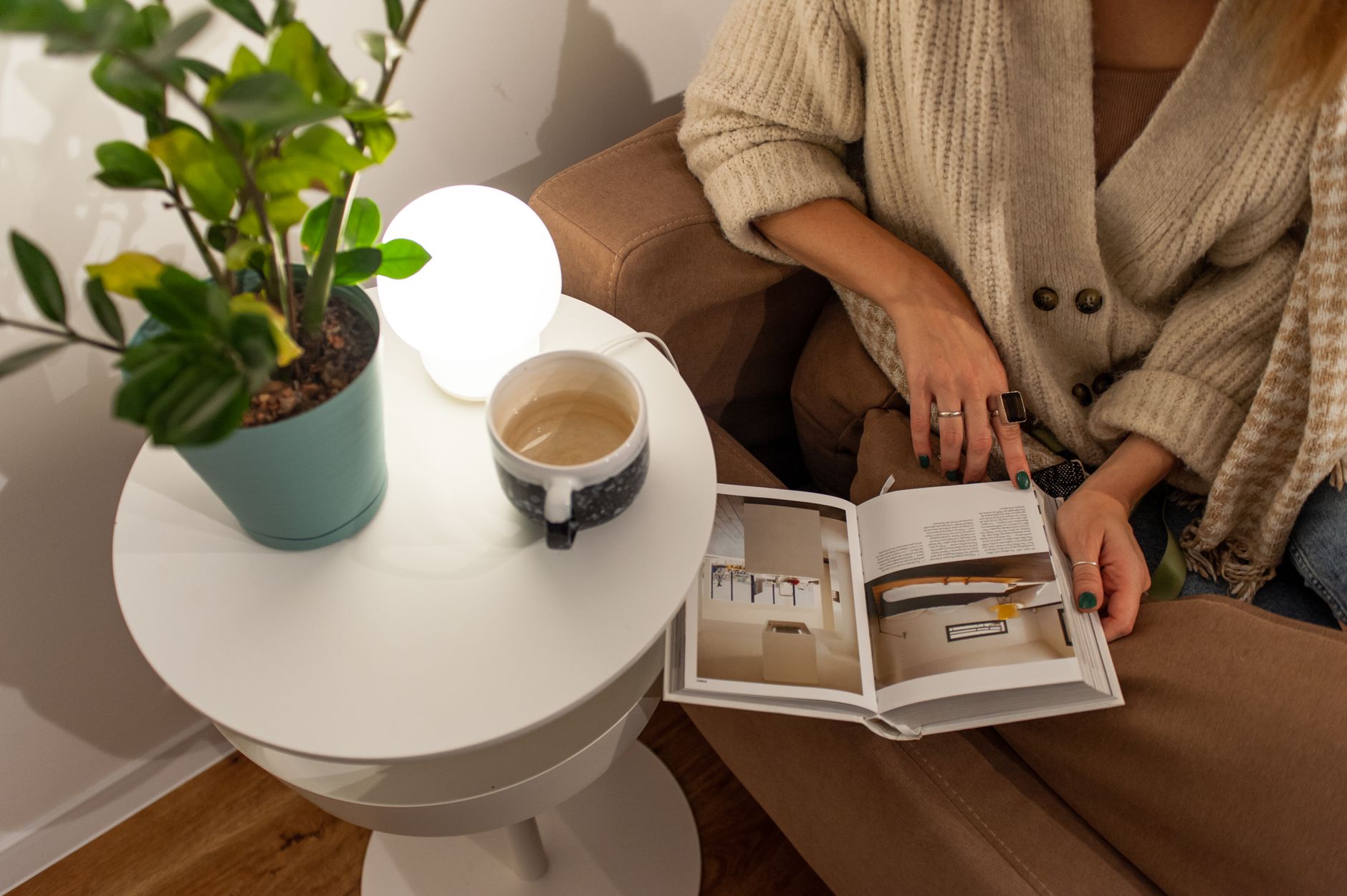 A calm waiting room with soft lighting, a pregnant woman holding a coffee mug, reading a brochure about prenatal screening