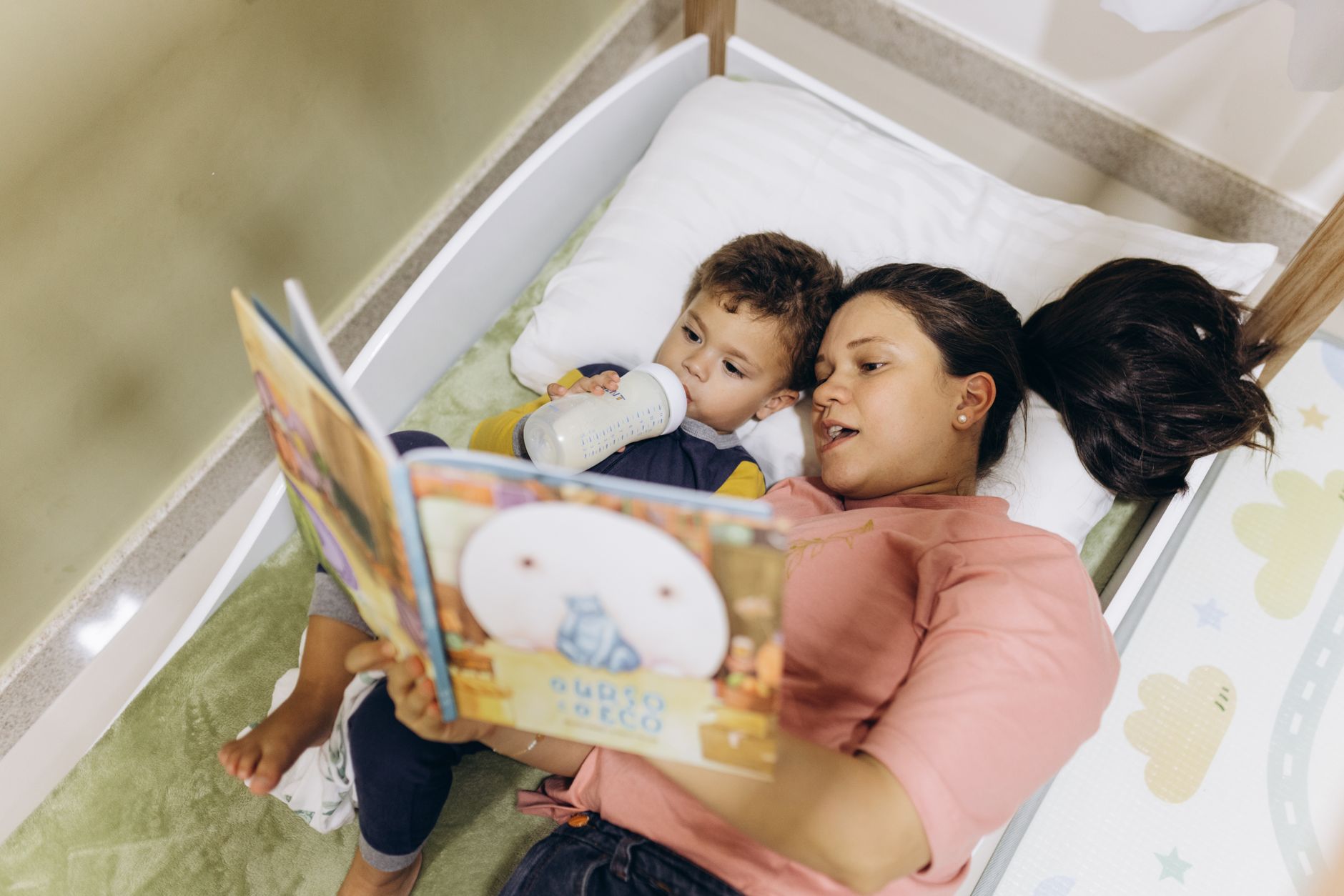Mother reading to toddler with newborn nearby