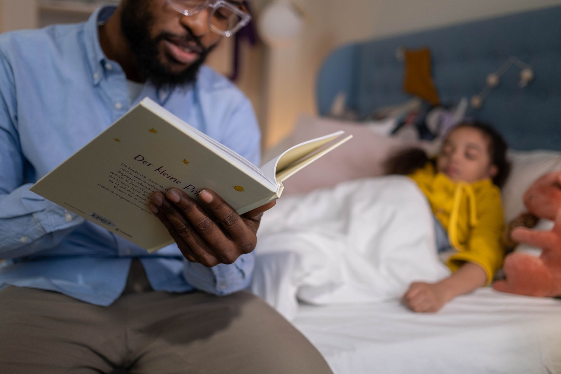 A parent sitting on a rug, reading a colorful picture book to a smiling 4-year-old, with a baby sleeping peacefully in a bassinet next to them, depicting a calm family routine.